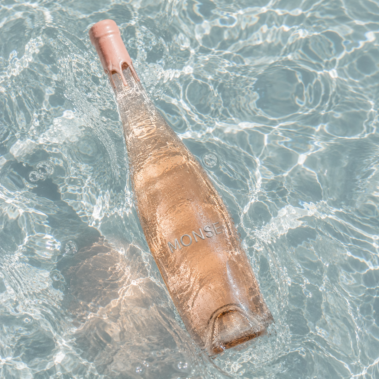 MONSE rosé bottle floating in clear pool water